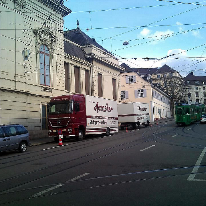 Zwei Möbelwagen der Oswald Auracher Möbelspedition im Einsatz in der Innenstadt von Basel vor historischem Gebäude