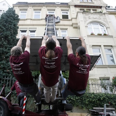 Mitarbeiter der Möbelspedition Auracher fungieren als Gegengewicht zur Stabilisierung des Außenaufzugs bei einem Umzug in Stuttgart